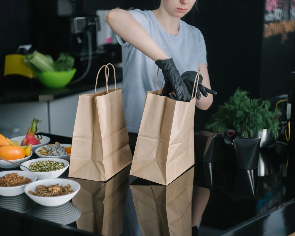 Сотрудница кухни упаковывает заказы в бумажные пакеты