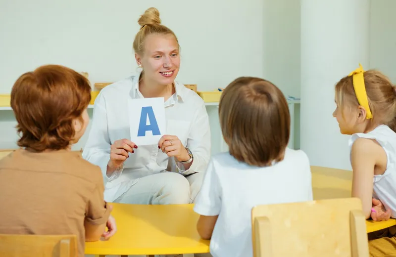 Преподаватель показывает детям карточку с буквой